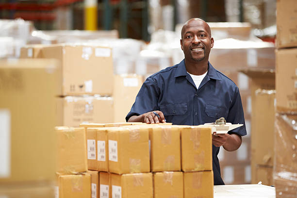 Worker In Warehouse Preparing Goods For Dispatch Smiling To Camera